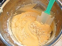 小麦粉を加え、ゴムベラで静かに混ぜ合わせ、溶かしバターを加え、混ぜます。<br />