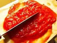 水煮トマトをまな板に載せ、粗くみじん切りにする。ニンニクも皮をむき、みじん切りにしておく。