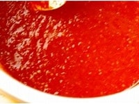 ハンバーグにかけるトマトソースを作る。ホーロー製の鍋にトマトと水、塩を入れ、フタをして弱火にかける。トマトが軟らかくなったら裏ごして皮を取り除き、さらに煮詰める。カラメルのような香りが出て、焦げ付かない程度に煮詰まったらできあがり。一度に大量に作るとよりおいしくできる。<br />