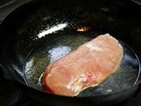 鶏の皮においしそうな焼色がついたら、水を加え、そのままフタはせず、15分ほど蒸し焼きにする。<br />