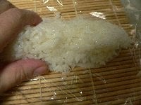 すし飯を棒状にまとめてサンマの上にのせ、両手で軽く押さえて形をつくる。