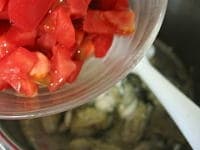 カキが色付いたら、トマトを加え、引き続き炒めます。<br />