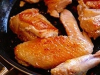 塩豚を取り出し、今度は鶏の手羽先、手羽元ぶつ切りにした鶏もも肉を皮目からフライパンに入れ、中火で焼色をつける。中まで火を通す必要はない。 <br />