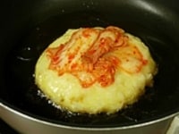 フライパンにごま油を熱して、お玉で卵ごはんを7cm位に丸く広げます。キムチをのせ中火でこんがりと焼き目がついたら裏面も焼きます。