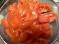 トマトを熱湯に1分間浸し、穴のあいた玉じゃくしですくい、冷水に浸して水を切り、ヘタと皮を取って2センチ角に切り、ザルに上げて水気を切る。