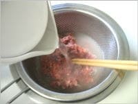 ざるにあけたコンビーフに熱湯をかけ、菜箸で軽くほぐします。