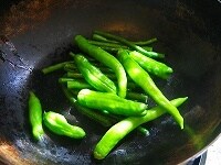 別のフライパンに油をしき、しし唐、インゲンなどの青味の野菜を炒めます。<br />