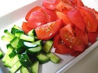 トマト、きゅうりを適当な（ブレンダーにかけやすい）サイズにカットします。トッピング（浮き実）となる夏野菜を、細かめの角切りにします。<br />