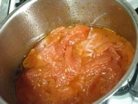 1にトマトの水煮缶を加え、木べらでトマトを潰すようにする。鍋にトマトの水煮缶を入れるとはねることがあるので注意。