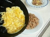 ボールに卵を割り、軽くほぐし、薄く塩コショウする。熱したフライパンに油を入れ、卵液を流し入れて箸でかき混ぜ、半熟になったらそばめしの上にのせる。 （卵は、白と黄色のコントラストを生かすために、あまりかき混ぜない。）青海苔粉をふりかけ、トマトケチャップを絞り、手で砕いたベビースターラーメンをトッピングする。 <br />