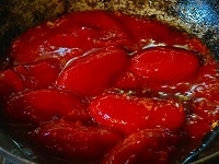 ニンニクから香ばしい匂いが漂い始めたら、ホールトマトを煮汁ごと加え、トマトを木じゃくしなどで潰してなめらかにしながら、弱火で20分～30分ほど、ペーストのちょっと手前ぐらいの濃さになるまで煮込みます。
