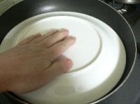 フライ返しを餃子の皮とフライパンの間に差し込んで、くっついていないか、フライパンを揺すって動くかどうかを確かめたら、皿をかぶせる。 逆さにして皿の上に取り出す。