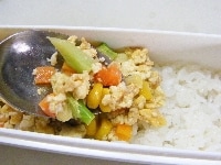 お弁当箱にごはんを詰め、その上に炒り豆腐をのせて、端に紅生姜を添える