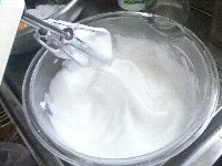 卵白をほぐし、塩を加えてハンドミキサーで7分立て（しちぶたて）にし、砂糖を2回に分けて加え、角がピンと立つまで泡立て、メレンゲを作る。 <br />