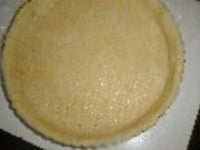 麺棒で厚さ5ミリ程度に伸ばし、バターを塗ったパイ皿に敷きつめる。フォークで突いて空気穴をあけ、ラップして冷蔵庫に入れ15分程休ませ、180～190℃のオーブンで15分間焼く。