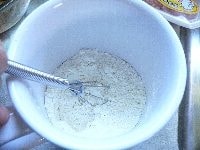 電子レンジ対応のマグカップに、小麦粉を計り入れ、ベーキングパウダー、砂糖、塩を加えてよく混ぜる。　次に水を加えて混ぜる。
