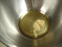 ボウルに、ごま油(大さじ1)とおろしニンニクを入れ混ぜ合わせます。<br />