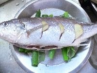 身に深く切り込みを入れ、腹の中、切り目、魚全体に塩をふる。 切り目に生姜をはさみ込み、長ねぎの青い部分を敷いた皿の上にのせる。