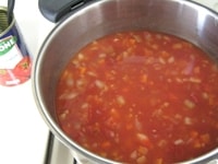 トマトの水煮缶と、その缶で1缶分の水、コンソメを加え、混ぜます。<br />
蓋をして、中火～弱火の火加減で、約20分煮ます。