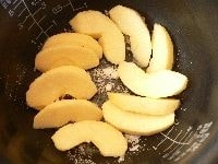 りんご1個を4つ割りにし、皮と芯を取って更に4等分のくし型にする。内釜にバターを薄く塗り、釜底に砂糖を大さじ1/2ふり、りんごを敷き詰め、レモン汁をふりかけ、砂糖大さじ1/2をふりかける。