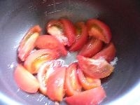 トマトはくし型に切って、薄くサラダオイルを塗った内釜の底に、真ん中を空けて敷き詰め、砂糖大さじ1杯をふりかける。バターを電子レンジで溶かす。