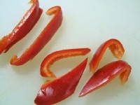 赤ピーマンは種とワタをとって、縦1cm幅に切り、ななめ横半分に切る<br />