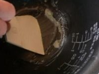 溶かしバターを作った器から、ゴムベラでバターをすくい取って、内釜にぬる。