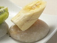 餅生地で栗の甘露煮を包み、手に片栗粉をつけて、手の平の上で形を整え、大きく切ったバナナを差し込む。