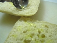 チャパタパンは、横半分にスライスし、オーブントースターなどであたため、パンの内側にオリーブオイルをかけて塗る。<br />