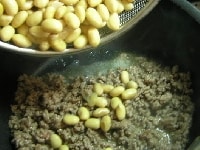 ひき肉の色が変わったら、ゆでた大豆を加え、さらに炒める。<br />