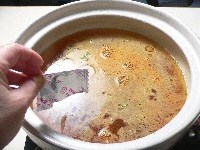 土鍋に水を入れて火にかけ、沸いたら酒とラーメンのスープを入れる。