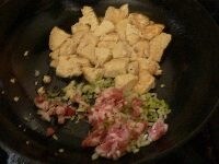豆腐を向こう側に寄せ、肉、ネギの半量、ニンニクを炒める。