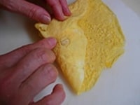 薄焼き卵の手前を折り、両端を折ってちらしすしを包みます。