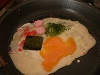 紅生姜、青海苔粉、魚肉ソーセージ、海苔、卵をのせる。卵の黄身を突いて崩す。