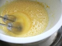 全卵と卵黄と砂糖を湯煎にかけながらハンドミキサーの高速で泡立てる。（3分間ほど） 湯煎の湯は、手を長く入れておけないほどの熱さで。