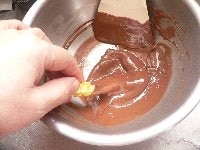 干し芋を手に持って、チョコにくぐらせる。