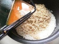 30分前にといだ米、発芽玄米を釜に入れ、ニンジンとゴボウの絞り汁を入れ、ワインを入れて、3合の目盛りまで水を足す。
