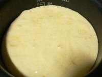 粉を広げて入れ、ボゥルを回しながら、ゴムベラで大きく混ぜ、温かいバターを入れ、底をすくうようにして混ぜ、りんごの上に流し入れて炊く。
