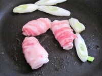 豚バラ薄切り肉はくるくると巻き、ネギは1cm幅程度に斜めに切る。<br />
フライパンにサラダ油を入れて中火にかけ、豚バラ薄切り肉とネギを炒める。