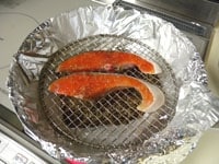 鮭をのせたら中火にかけます。5分ほどしたら煙が出てきます。煙を確認したら蓋をし、弱火で20分ほど燻製します。<br />