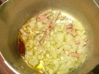 鍋にオリーブ油、たまねぎ、ニンニク、赤唐辛子、落花生、ベーコンを入れて弱火にかけ、じっくり炒める。<br />
<br />