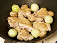 フライパンに油を入れ、中火で、鶏肉の皮面から焼きます。<br />
焼き色がついたら裏返し、脇にたまねぎ（ペコロス）、マッシュルームを加え、フライパンをゆすりながら、野菜に油がまわるよう、軽く炒めます。<br />