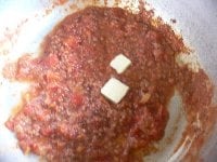 スパゲッティを塩を加えた湯で茹でる。鍋にミートソースを取って火を通し、バターと乾燥バジルを加える。