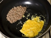 ハンバーグの種を崩して炒めます。同時に調理時間短縮のため塩を少々加えた、いり卵を作ります。 <br />