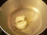鍋にオリーブオイルとニンニクを入れて火にかけ、弱火で1分炒め、たまねぎを加えて2分炒める。<br />