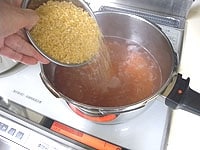 濾した果汁は、約1.100mlほど取れました。鍋に入れ中火にかけ沸騰したら、砂糖を加えます。アクが出てきたら取り除き、果汁が半分くらいになるまで、かき混ぜながら煮詰めます。<br />
