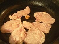 フライパンにオリーブ油とニンニクを入れて火にかける。ニンニクを炒めて、香りが立ったら鶏肉を並べる。<br />