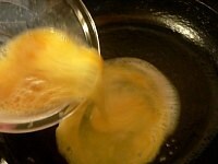 フライパンを火にかけてバターを溶かす。溶きほぐした卵を流し入れ、箸で大きくかき混ぜて半熟のスクランブルエッグを作る。<br />