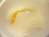 粉の真ん中に餅を流し入れ、溶き卵を入れる。<br />