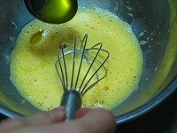 油をスプーンですくい、少しずつ、卵黄の中にたらしながら、泡だて器で混ぜていきます。
